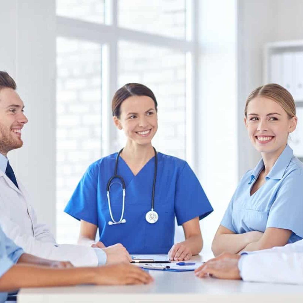 Home Care Services - Care Navigation. hospital, profession, people and medicine concept - group of happy doctors with tablet pc computers meeting at medical office