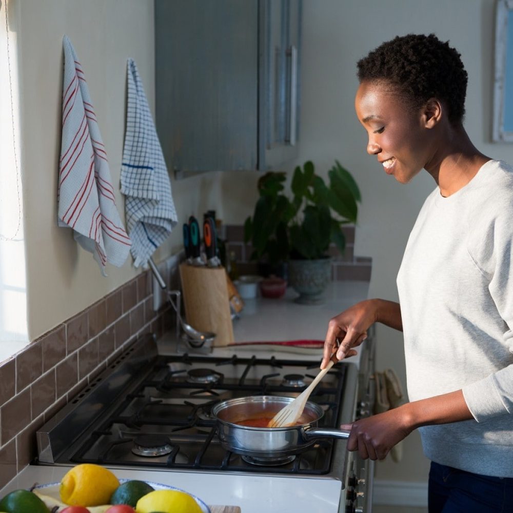 Home Care Services - Cooking, light housekeeping, and laundry. Woman cooking in kitchen.