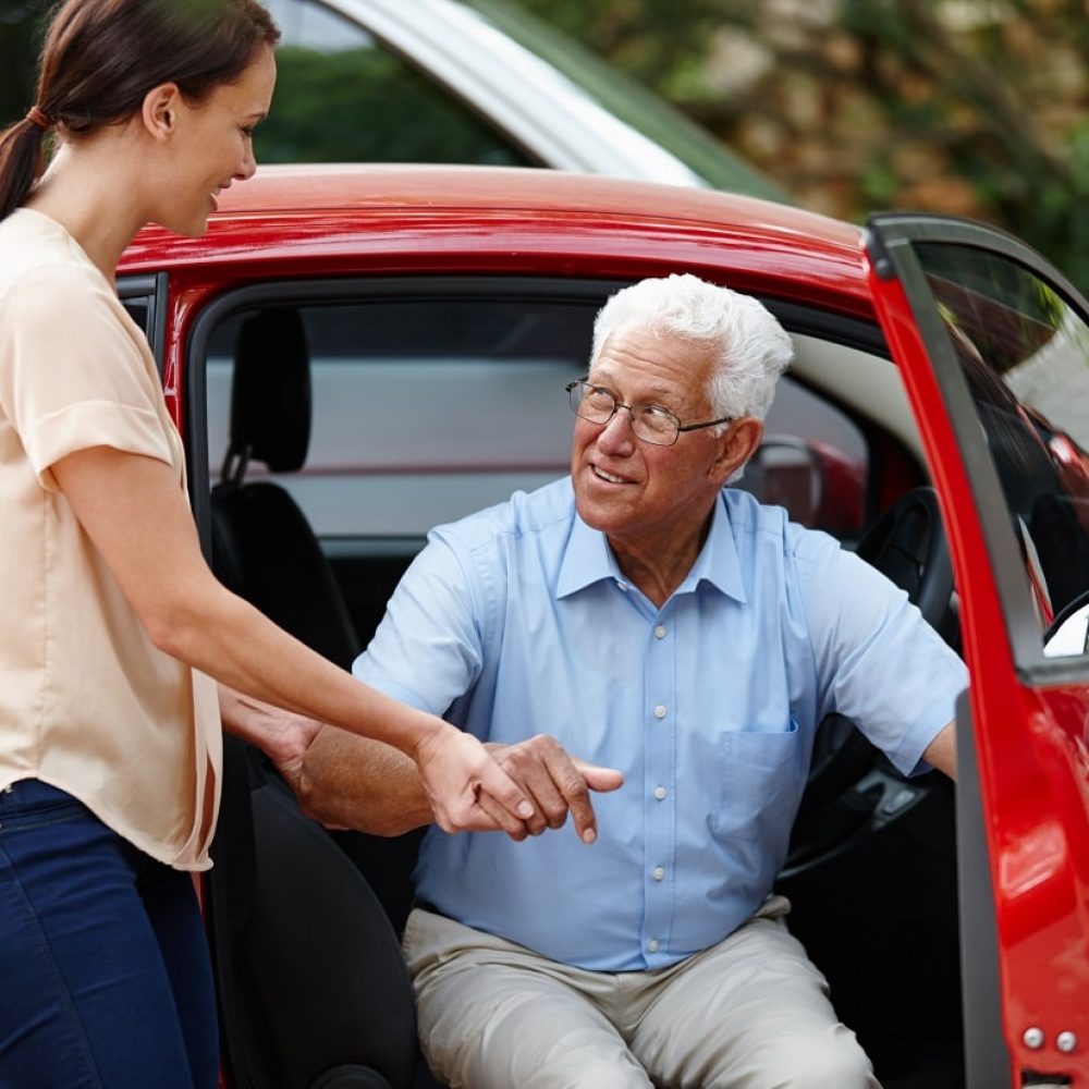 home care services - Transportation. Image of a woman helping her senior father out of the car
